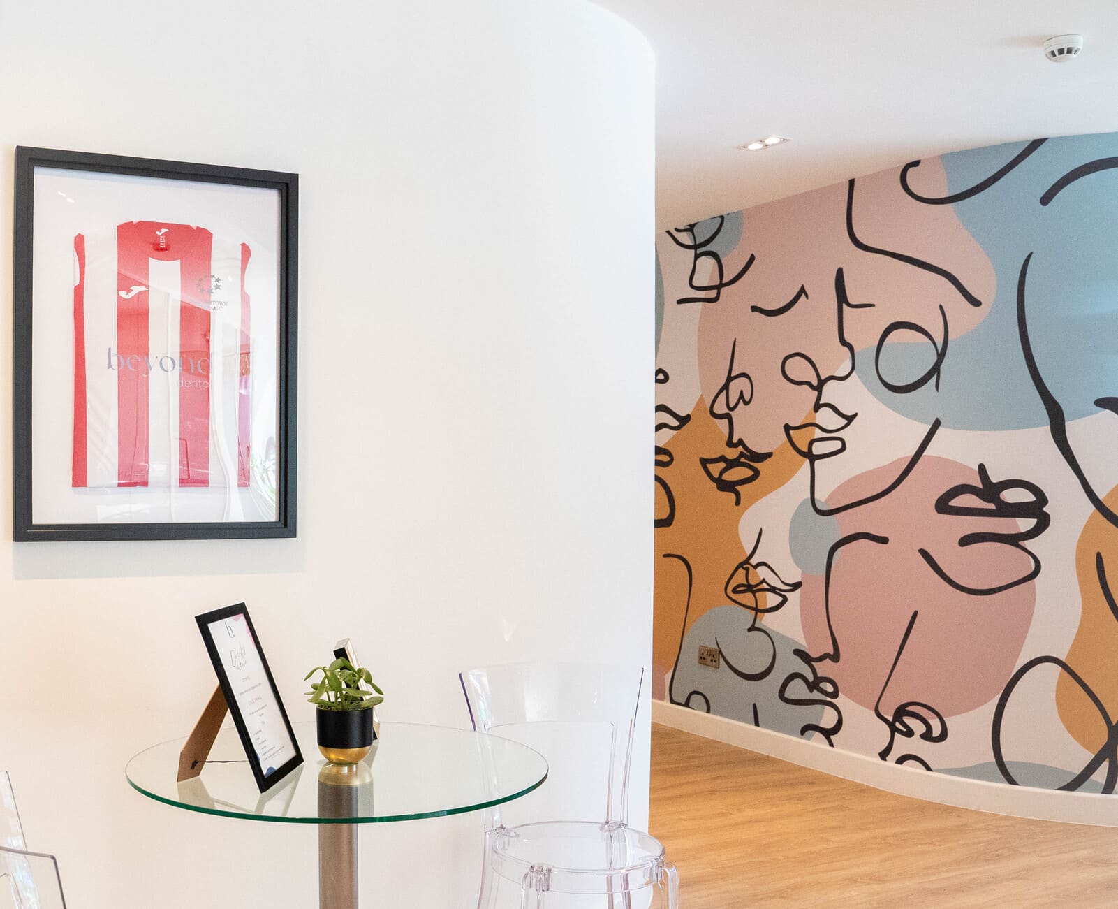 Dental clinic wall with framed jersey and colorful abstract mural.
