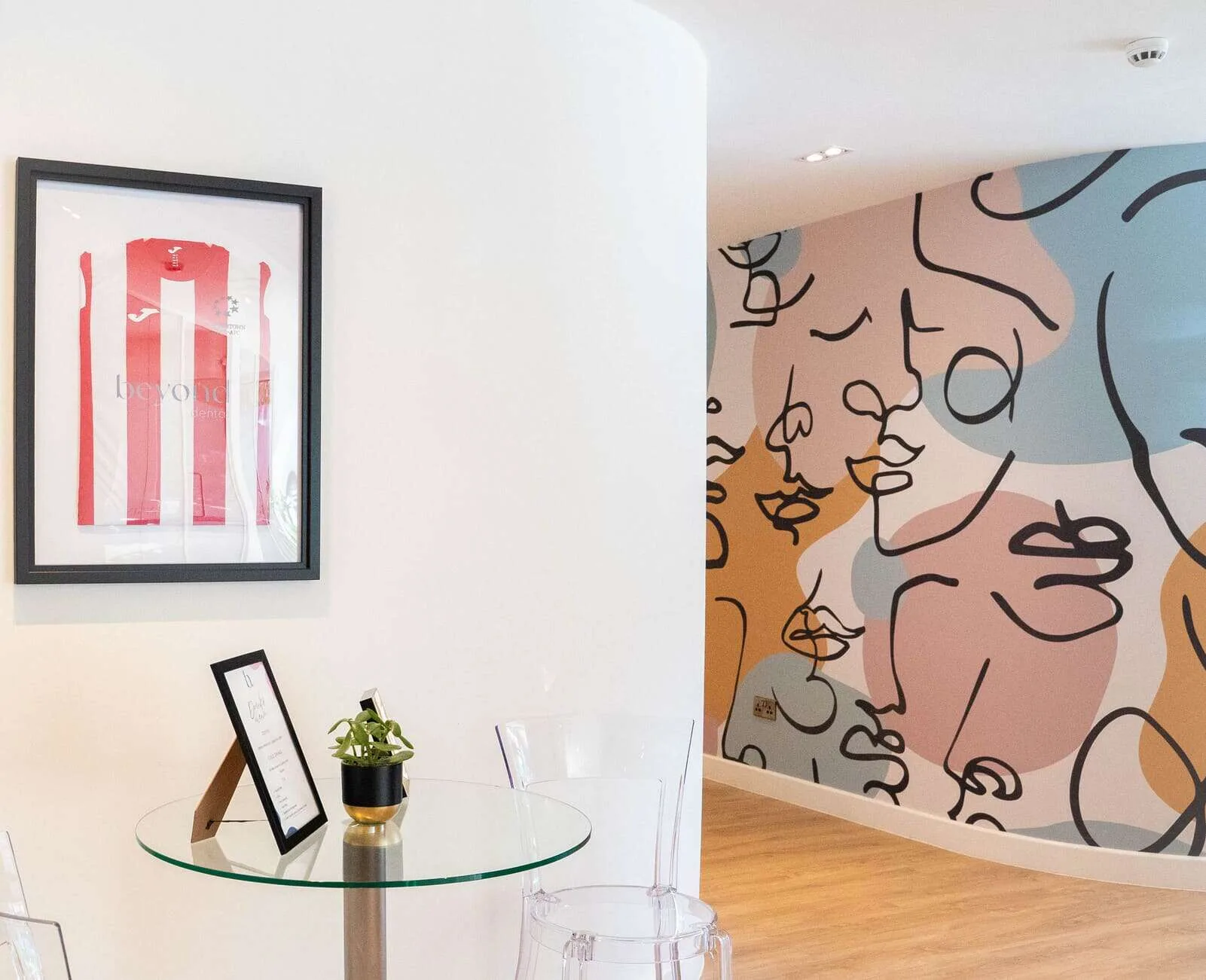 Dental clinic wall with framed jersey and colorful abstract mural.