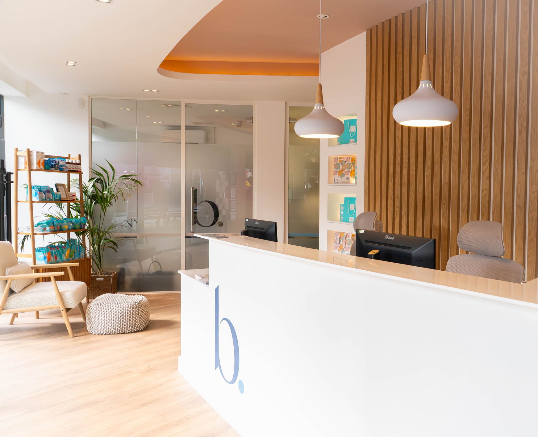 Dental clinic reception desk with pendant lights and product display shelf.