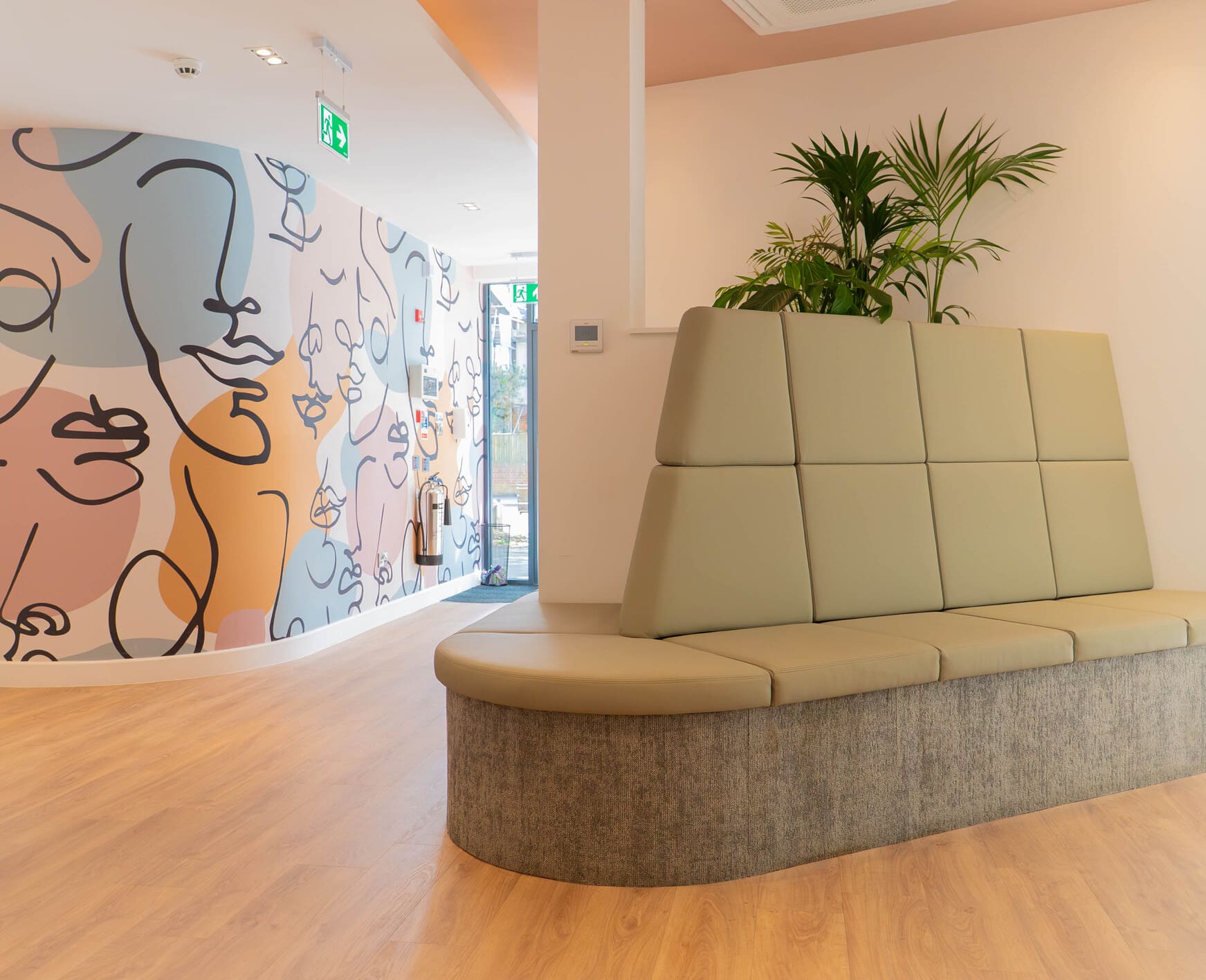 Dental clinic seating booth with plants and abstract mural wall.
